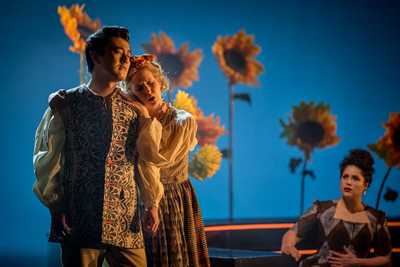 A woman is holding a man, leaning her head on his shoulder as she sings looking sad