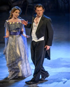 A man and woman in extravagant formal clothes argue - the man visibly disgruntled, the woman baffled